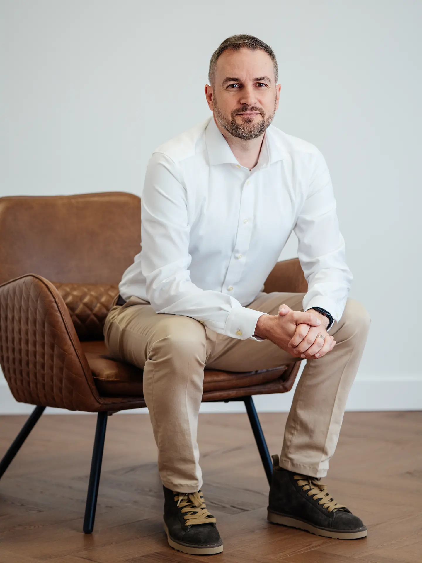 Michal Balaz seated in a leather chair, wearing a white shirt